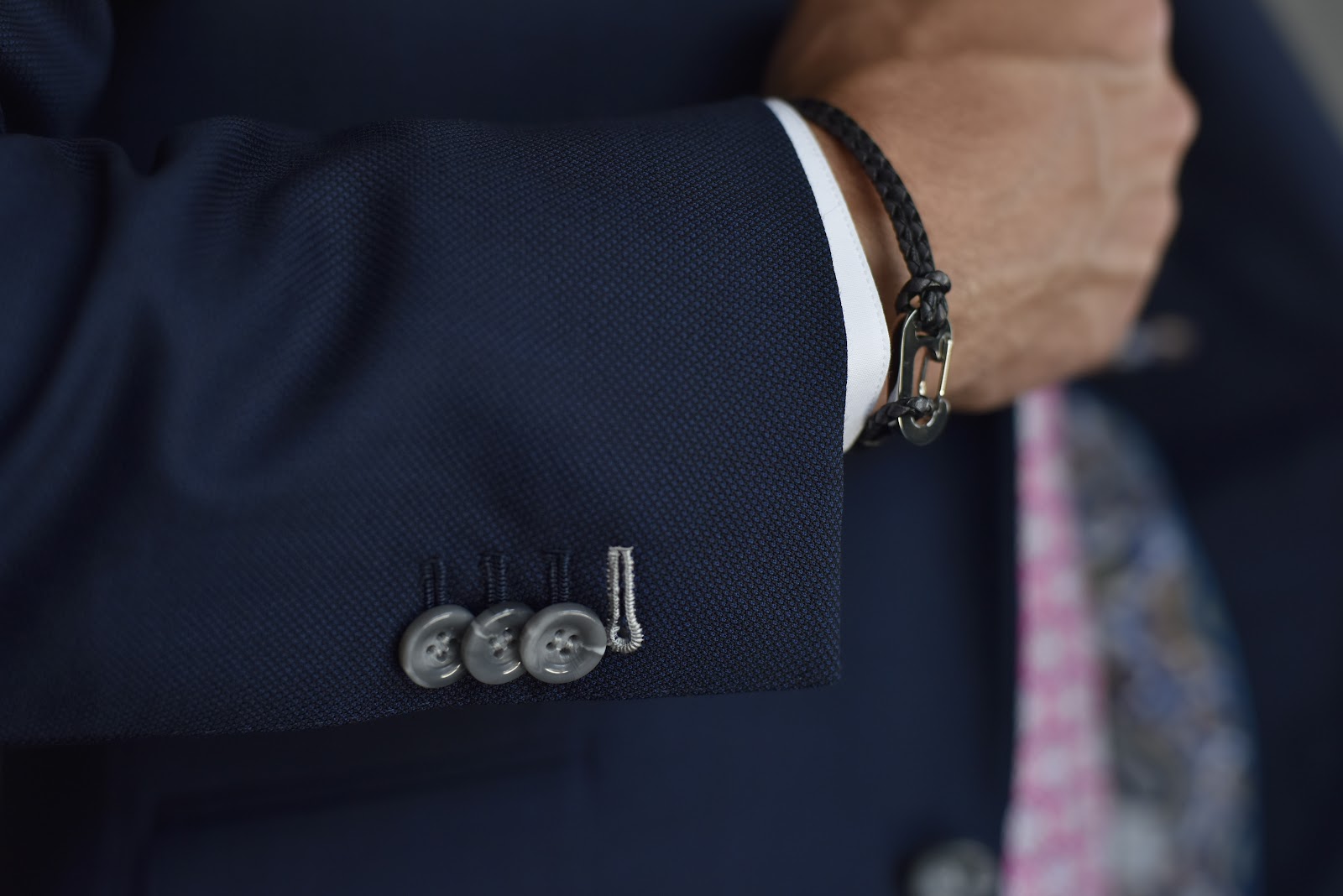 Detail shot showing textured working buttons on the sleeve of a custom tailored suit jacket
